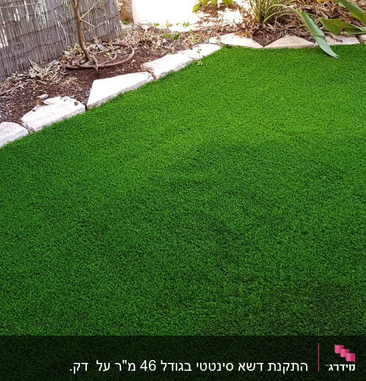 דשא סינתטי מוקף באבנים בגינה קטנה